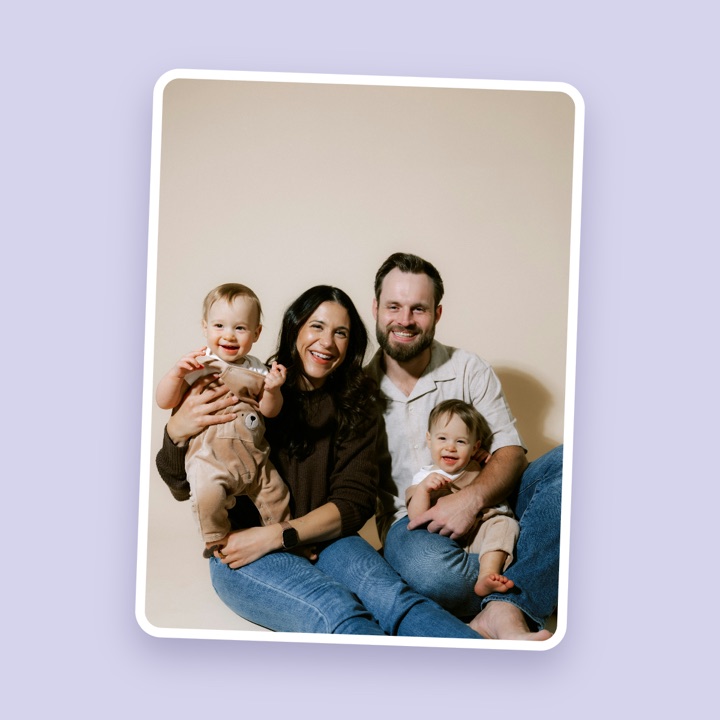 An unedited family photo of two parents and two smiling babies